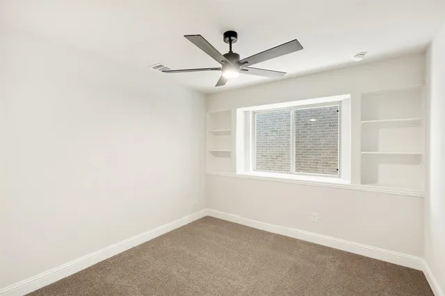an empty room with a window and a fan