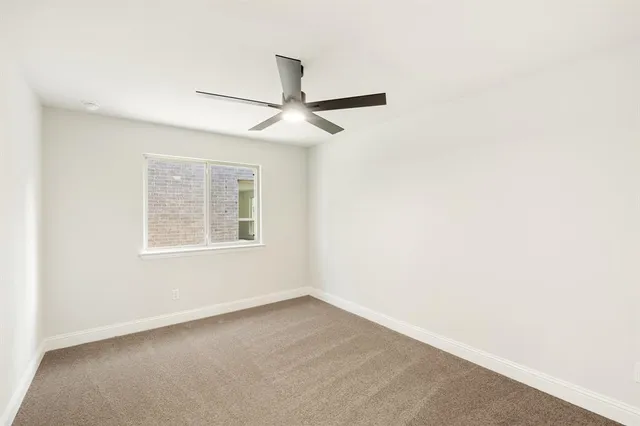 an empty room with a window and ceiling fan