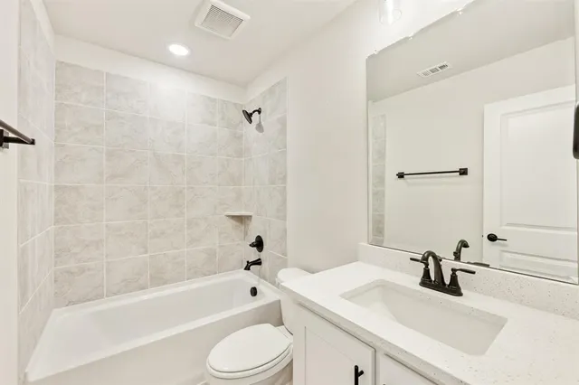 a bathroom with a bathtub shower sink vanity mirror and toilet