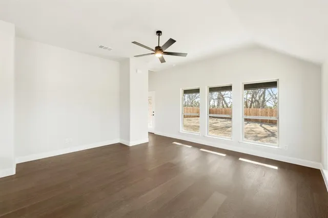 an empty room with wooden floor fan and windows