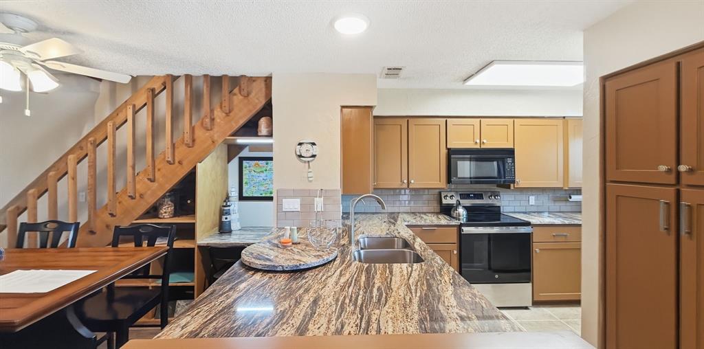 3037 Hells Gate Loop, Unit C208 Strawn, TX 76475 - Photo 12 of 24 a kitchen with stainless steel appliances kitchen island granite countertop a sink and cabinets