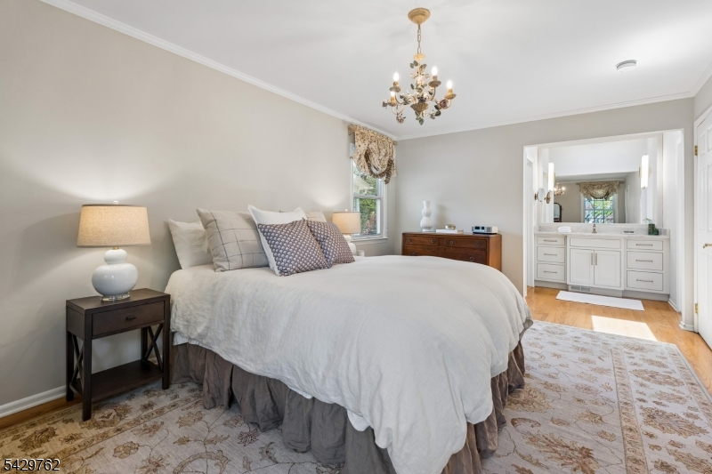 738 Springfield Avenue Summit, NJ 07901 - Photo 16 of 29 a spacious bedroom with a bed and a chandelier