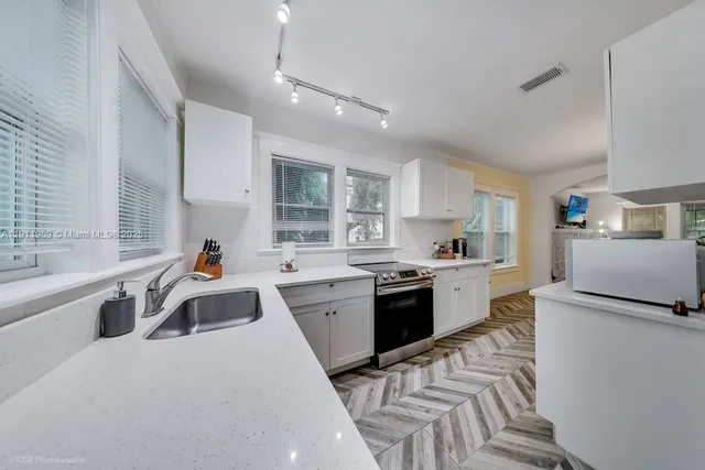 a large kitchen with stainless steel appliances granite countertop a sink dishwasher a stove and a refrigerator with wooden floor