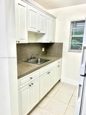 a kitchen with granite countertop white cabinets and sink
