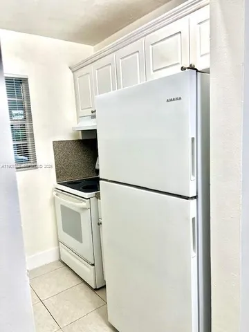 a white refrigerator freezer and a stove sitting inside of a kitchen