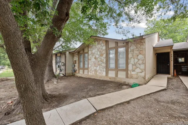 a view of a house with a tree in front of it