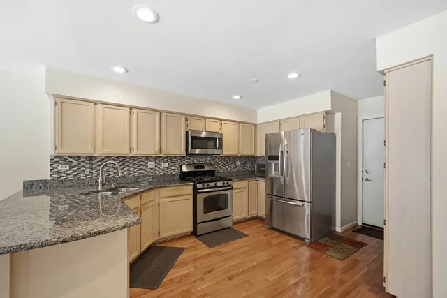 a kitchen with stainless steel appliances granite countertop a refrigerator a stove and a sink