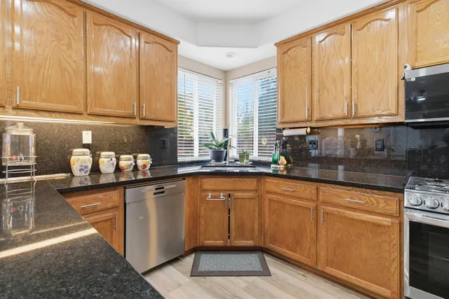 a kitchen with granite countertop a sink a counter space appliances and cabinets