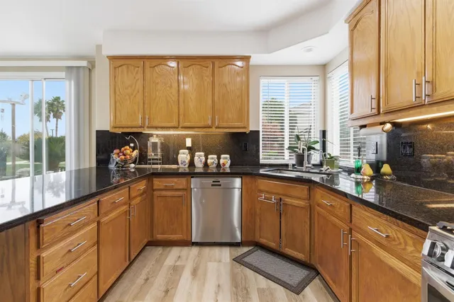 a kitchen with stainless steel appliances granite countertop a sink a stove and cabinets