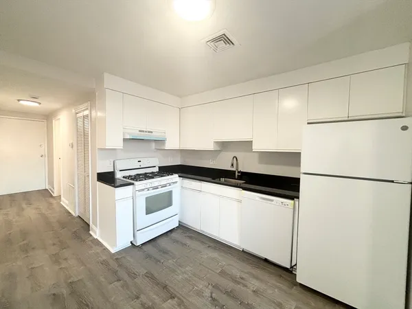 a kitchen with stainless steel appliances a refrigerator a sink and white cabinets