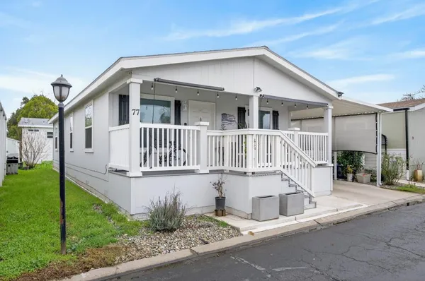 a white house that has a small yard and a large tree