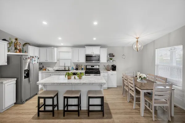 a kitchen with a dining table chairs and refrigerator