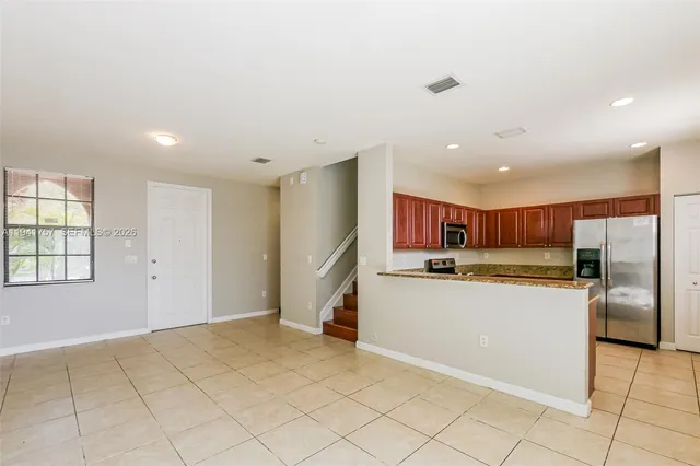 a kitchen with stainless steel appliances granite countertop a refrigerator and a stove top oven