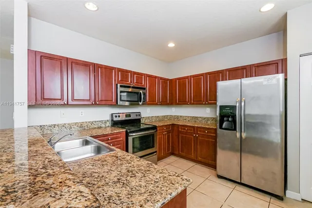 a kitchen with stainless steel appliances granite countertop a refrigerator sink and stove