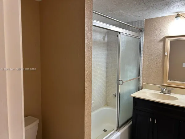 a bathroom with a shower sink vanity and mirror