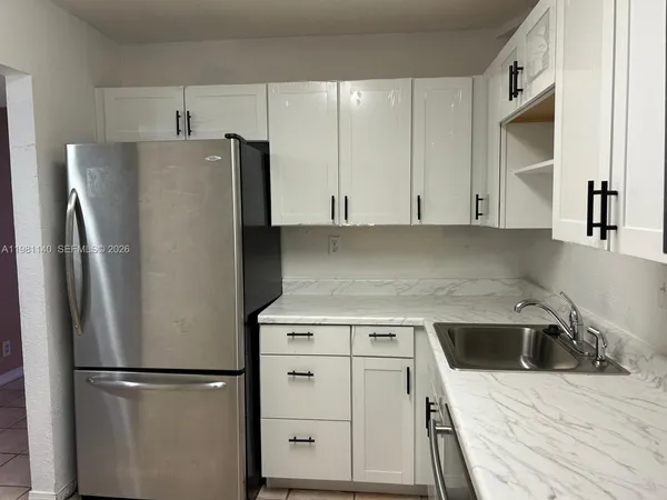 a kitchen with a refrigerator sink and cabinets