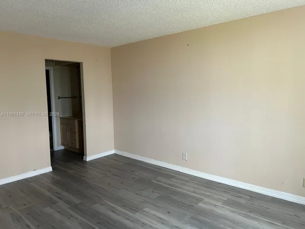 a view of an empty room with wooden floor and closet