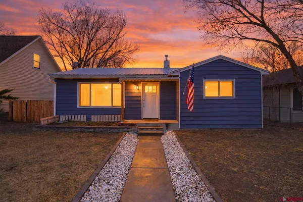 a view of a house with a small yard and a large tree