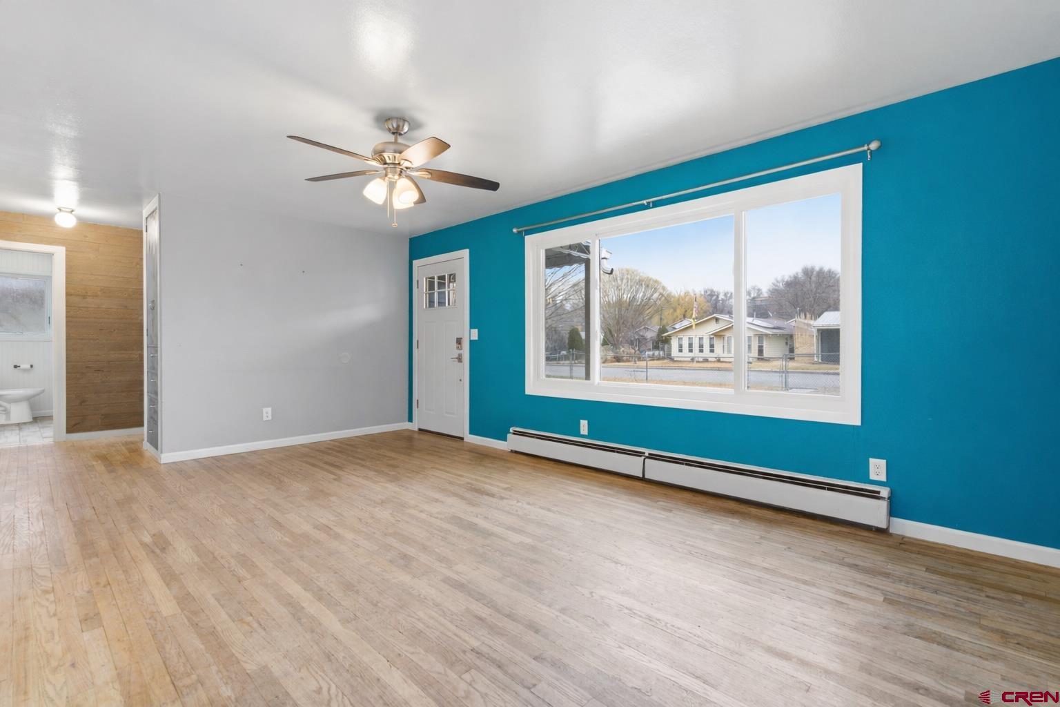 1029 Howard Street Delta, CO 81416 - Photo 4 of 17 an empty room with wooden floor chandelier fan and windows