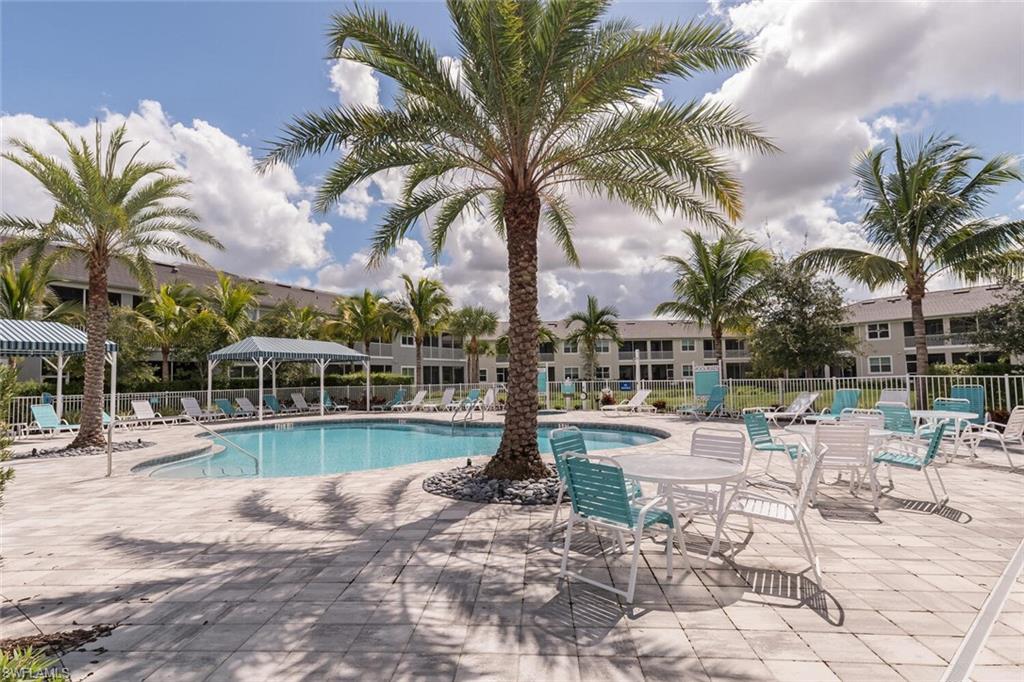 6934 Avalon Circle, Unit 401 Naples, FL 34112 - Photo 12 of 13 a view of a swimming pool with a table and chairs