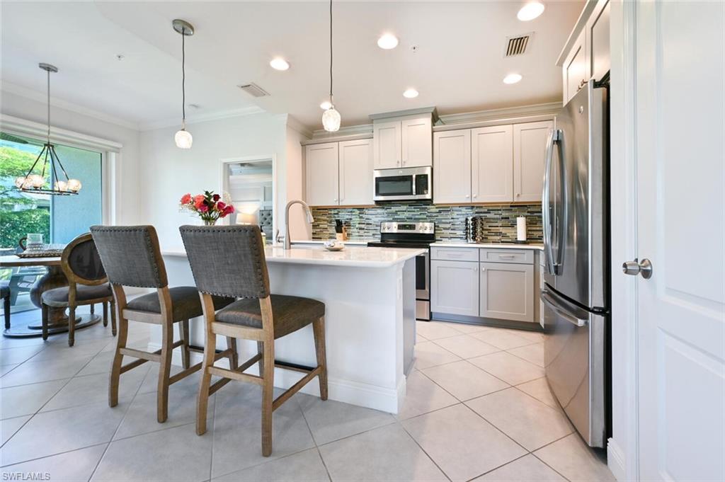 6934 Avalon Circle, Unit 401 Naples, FL 34112 - Photo 2 of 13 a kitchen with kitchen island a stove a table and chairs in it