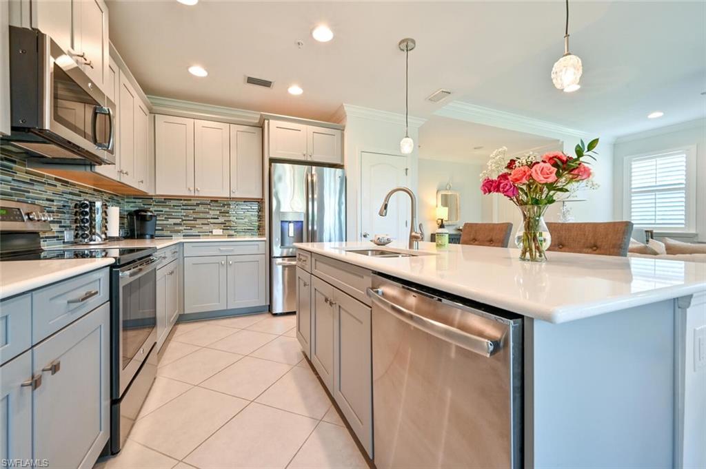 6934 Avalon Circle, Unit 401 Naples, FL 34112 - Photo 6 of 13 a kitchen with stainless steel appliances kitchen island granite countertop a sink and cabinets