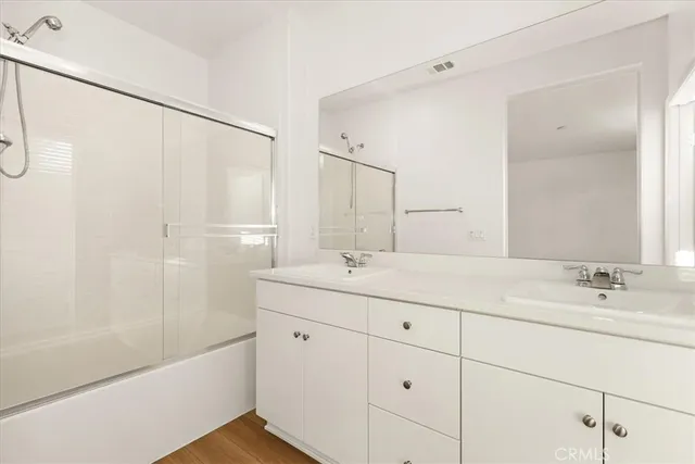 a bathroom with a double vanity sink a mirror and a bathtub