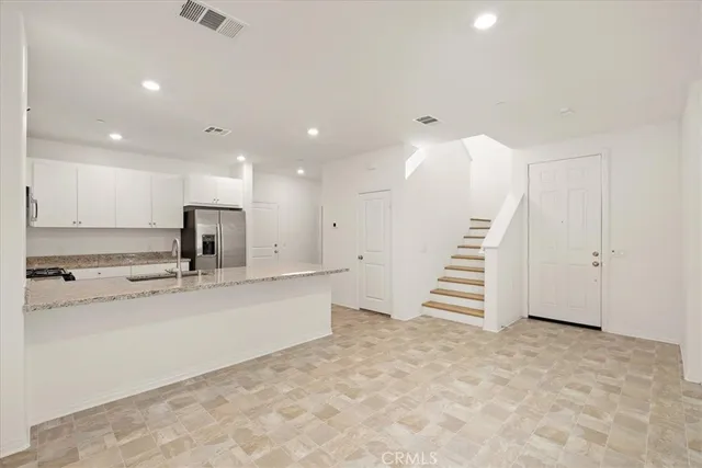 a view of kitchen with sink electronic appliances and stairs