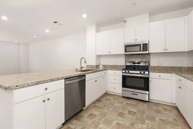 a kitchen with granite countertop white cabinets and white appliances