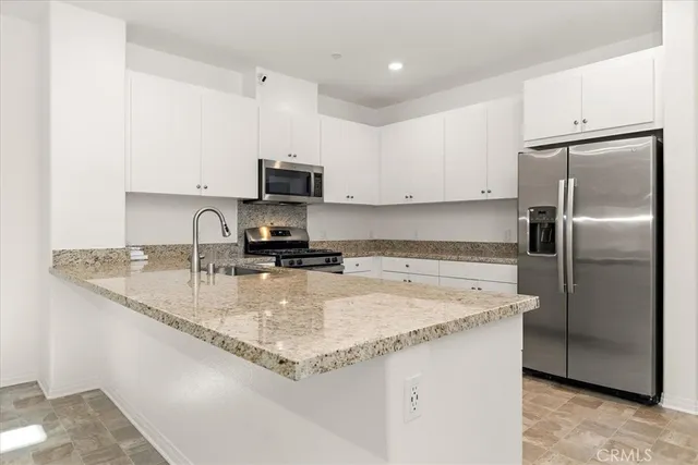 a kitchen with stainless steel appliances granite countertop a sink a refrigerator and a granite counter tops