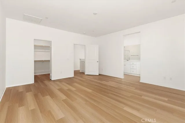 a view of an empty room with wooden floor and closet