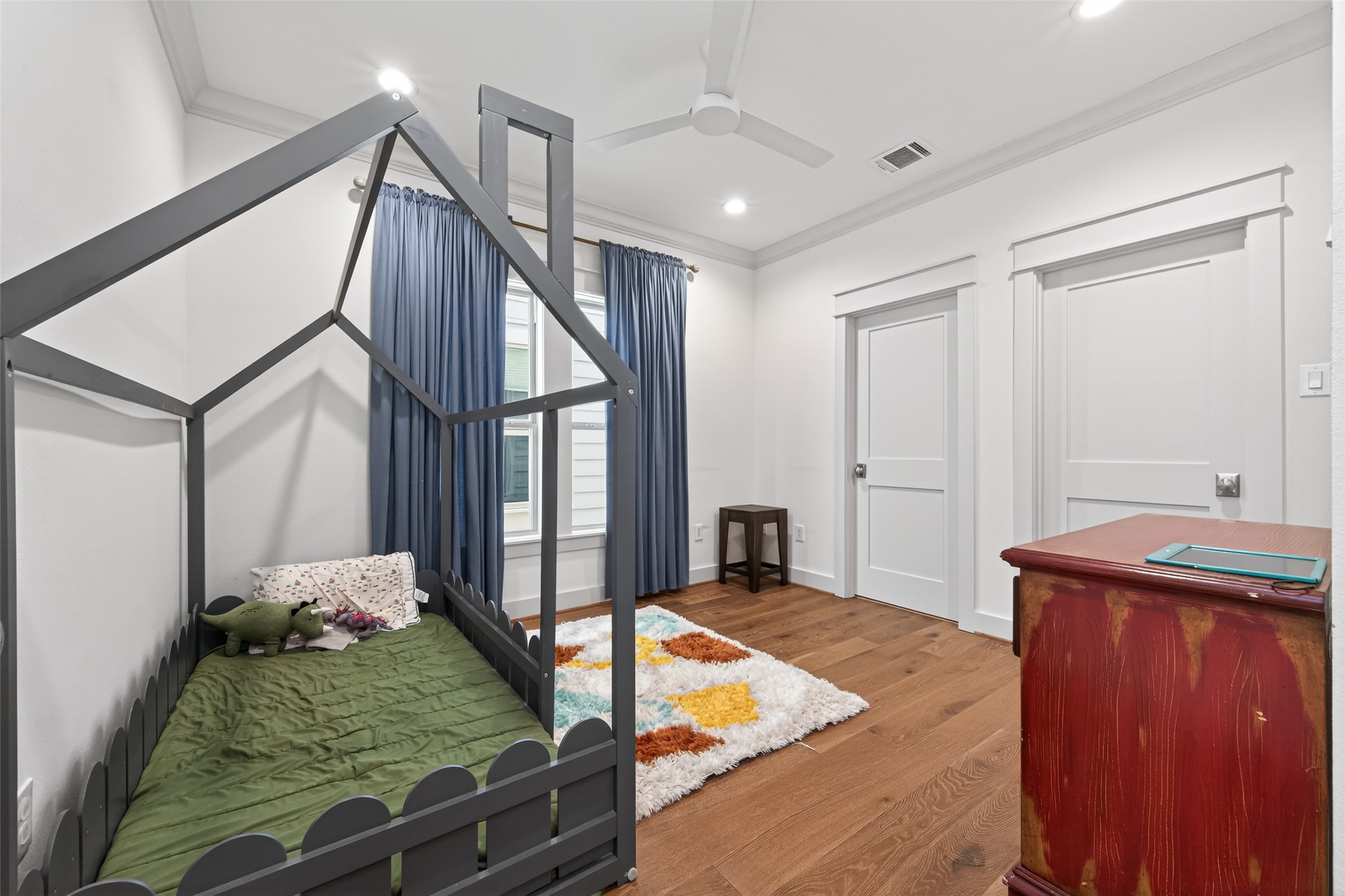 515 West 25th Street Houston, TX 77008 - Photo 20 of 35 Bright 11’1” x 11’11” secondary bedroom features large windows, crown molding, and a Minka-Aire large-room fan in flat white. The 4’7” x 6’1” walk-in closet offers built-in shelving, cubbies, and hanging racks for storage and organization.