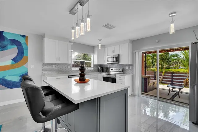 a kitchen with stainless steel appliances a dining table chairs stove and sink