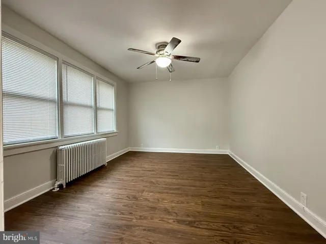 an empty room with wooden floor fan and windows