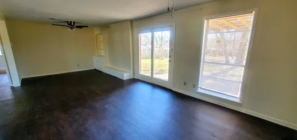 an empty room with wooden floor and windows