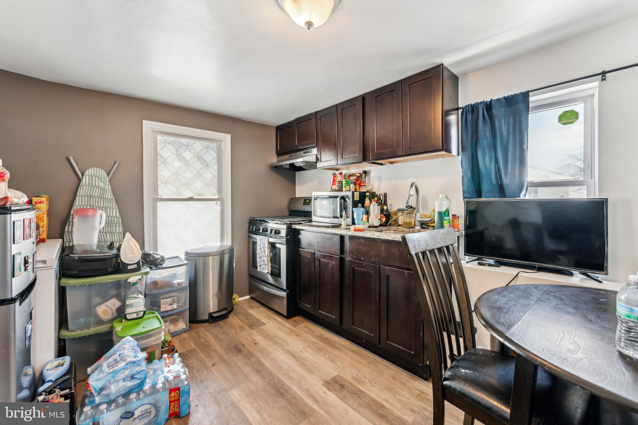 200 East Washington Street Riverside, NJ 08075 - Photo 22 of 31 a kitchen with stainless steel appliances a stove a refrigerator a sink a dining table and chairs with wooden floor