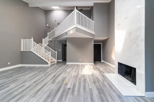 a view of an empty room with wooden floor and stairs