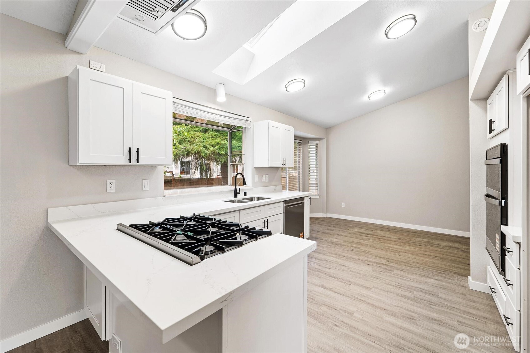604 213th Street Southwest Bothell, WA 98021 - Photo 13 of 40 a white kitchen with wooden floor stainless steel appliances and a window
