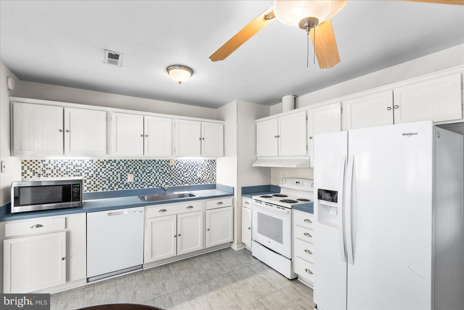 227 7th Street Colonial Beach, VA 22443 - Photo 12 of 36 a kitchen with white cabinets and white appliances