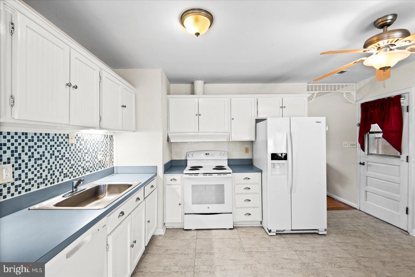 227 7th Street Colonial Beach, VA 22443 - Photo 13 of 36 a kitchen with stainless steel appliances a stove a refrigerator and white cabinets