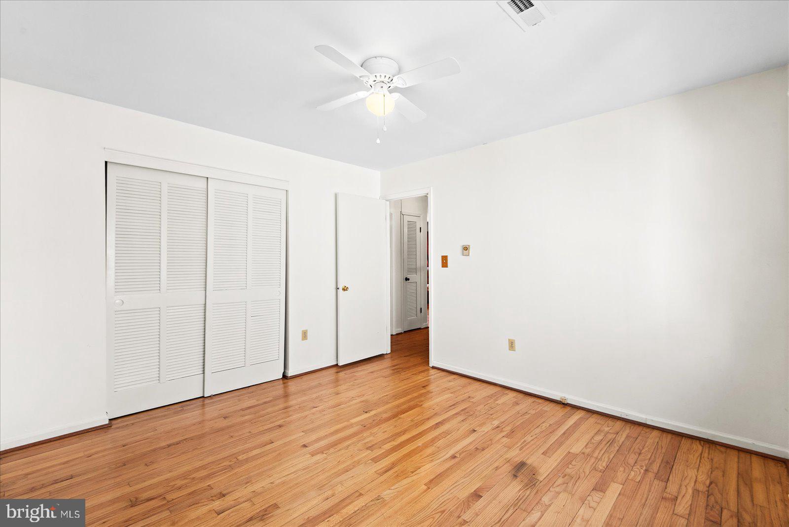 227 7th Street Colonial Beach, VA 22443 - Photo 21 of 36 an empty room with wooden floor and a ceiling fan