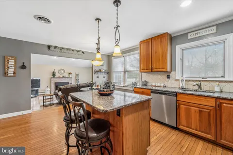 a kitchen with stainless steel appliances granite countertop a sink a stove a dining table and chairs