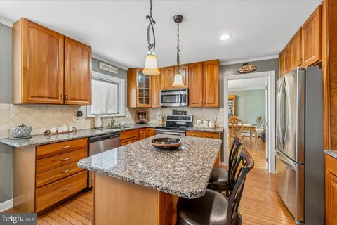 a kitchen with a stove a sink a kitchen island and chairs with wooden floor
