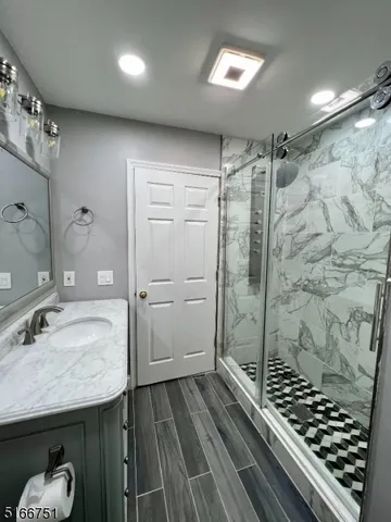 a bathroom with a granite countertop sink a mirror and shower