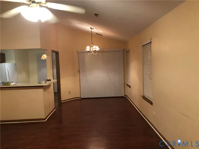 an empty room with wooden floor kitchen view and a window
