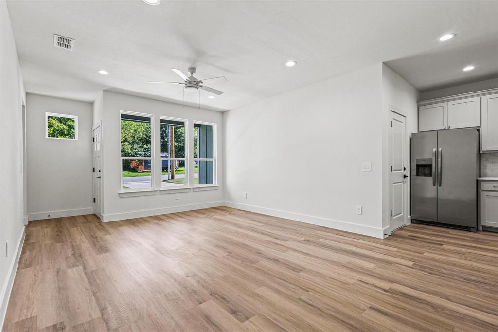 508 Florence Denison, TX 75020 - Photo 7 of 26 an empty room with wooden floor a ceiling fan and windows