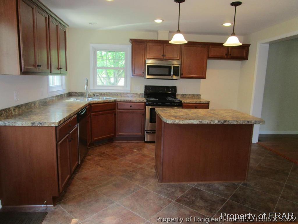 1373 Joel Road Carthage, NC 28327 - Photo 27 of 27 a kitchen with stainless steel appliances granite countertop a sink a stove top oven a window and a counter top space