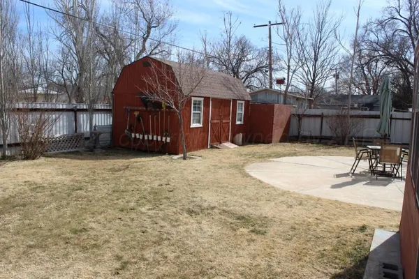 a view of a backyard with table and chairs and wooden fence