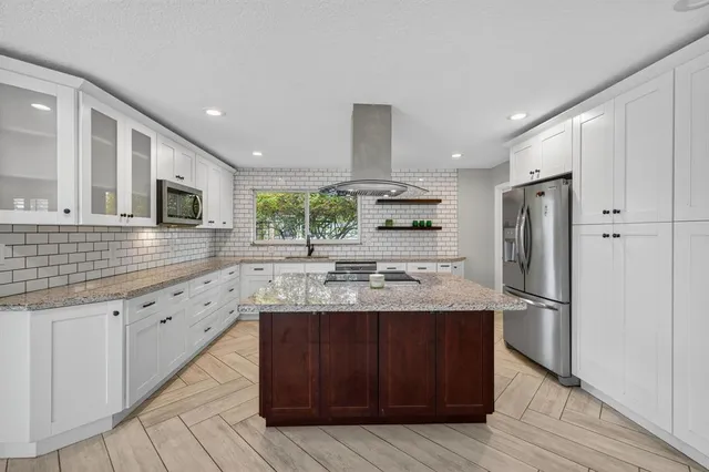 a kitchen with stainless steel appliances granite countertop wooden cabinets a refrigerator and a sink