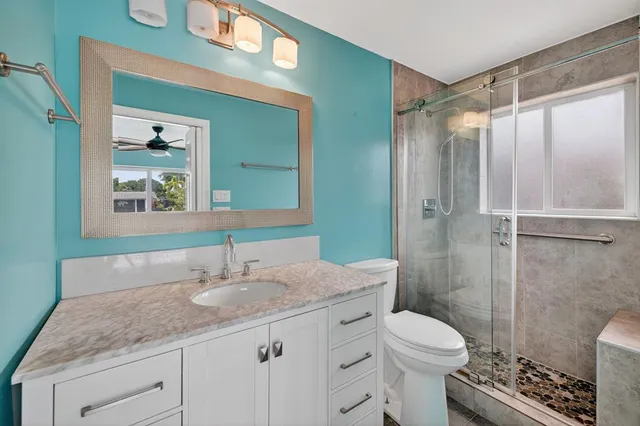 a bathroom with a granite countertop sink toilet and shower